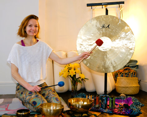 Fiona delivering a Gong Bath at an event in Leeds in a serene room with a large gong and singing bowls in the background